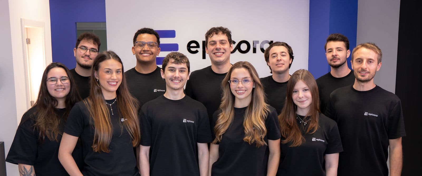 A equipe da Epicora no escritório em Chapecó, na parede do logo
